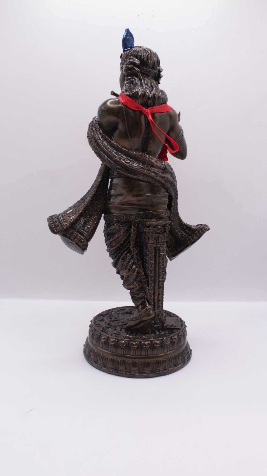 Dark finish resin Krishna statue playing flute, with garland, back view