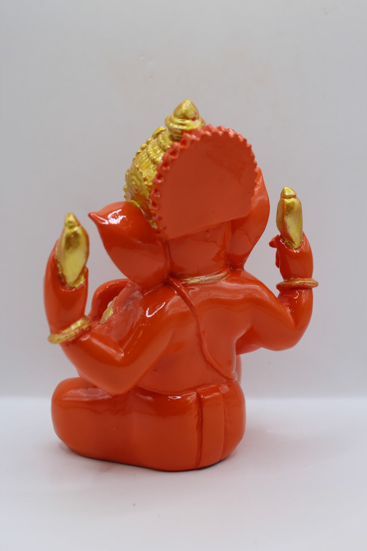 Orange resin Ganesh murti seated, gold crown, back view