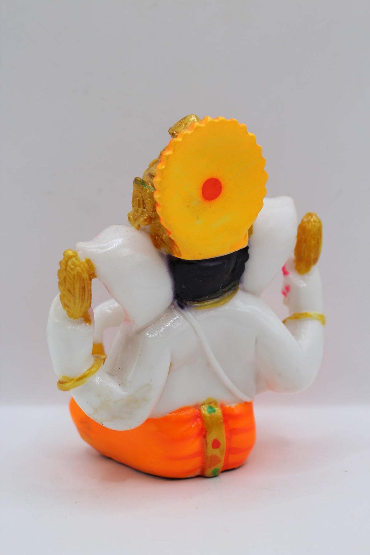 Small white resin Ganesh murti, orange dhoti, back view