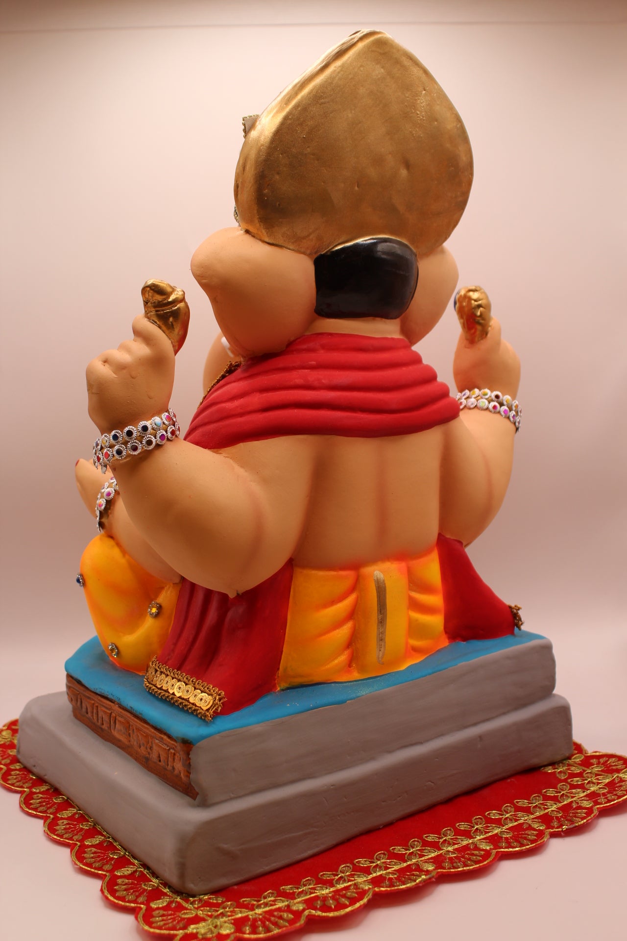 Back view – jewellery style idol with red khes and orange dhoti