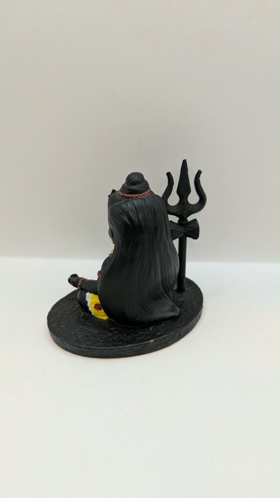 Small black sitting Shiva statue with trishul, back view