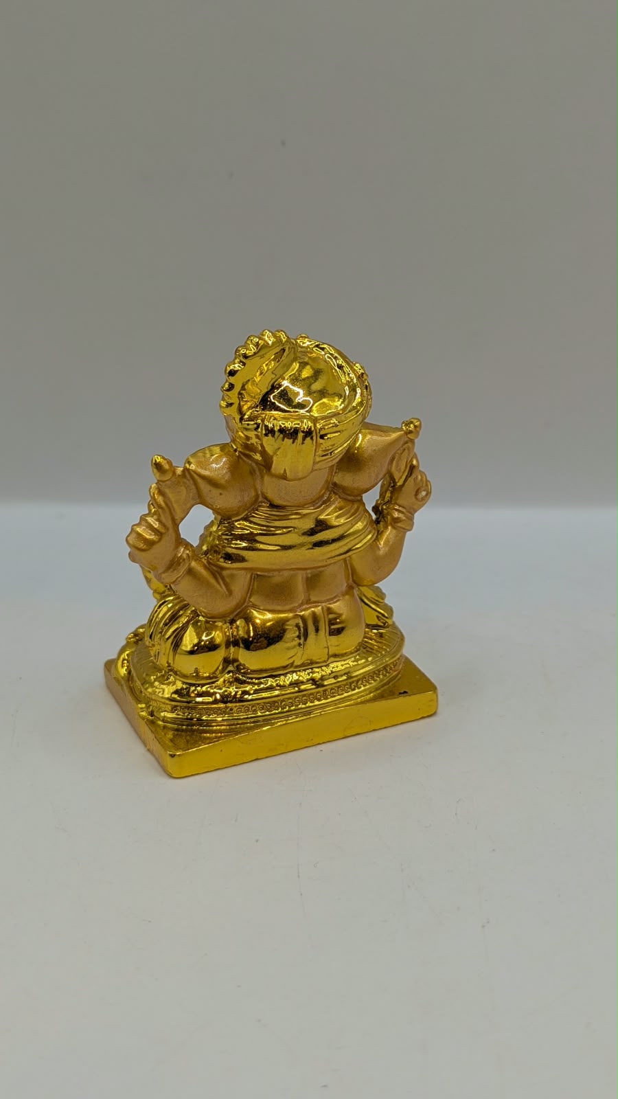 Gold Ganesh statue wearing a turban, back view