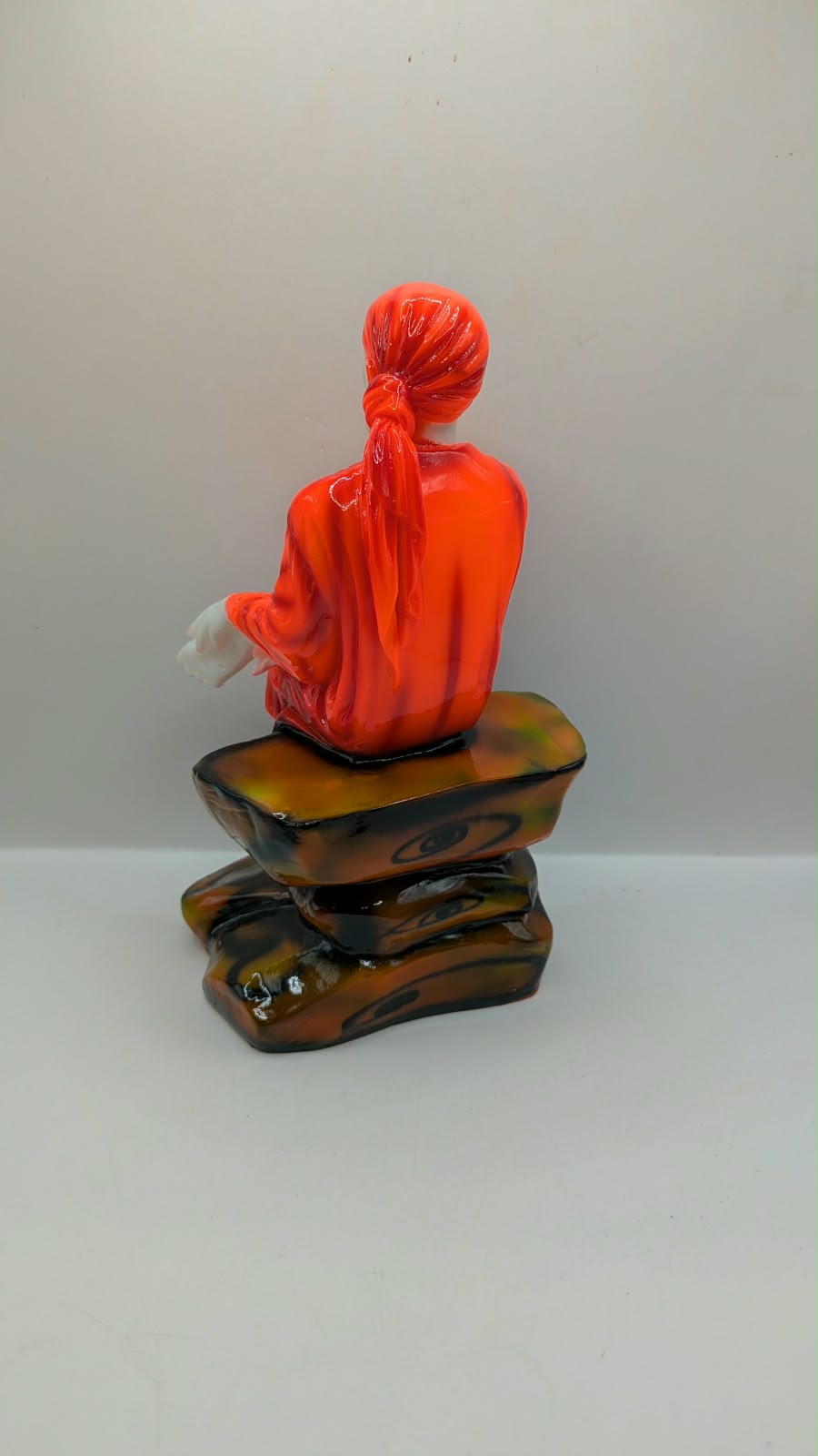 Sai Baba statue on rock seat, back view