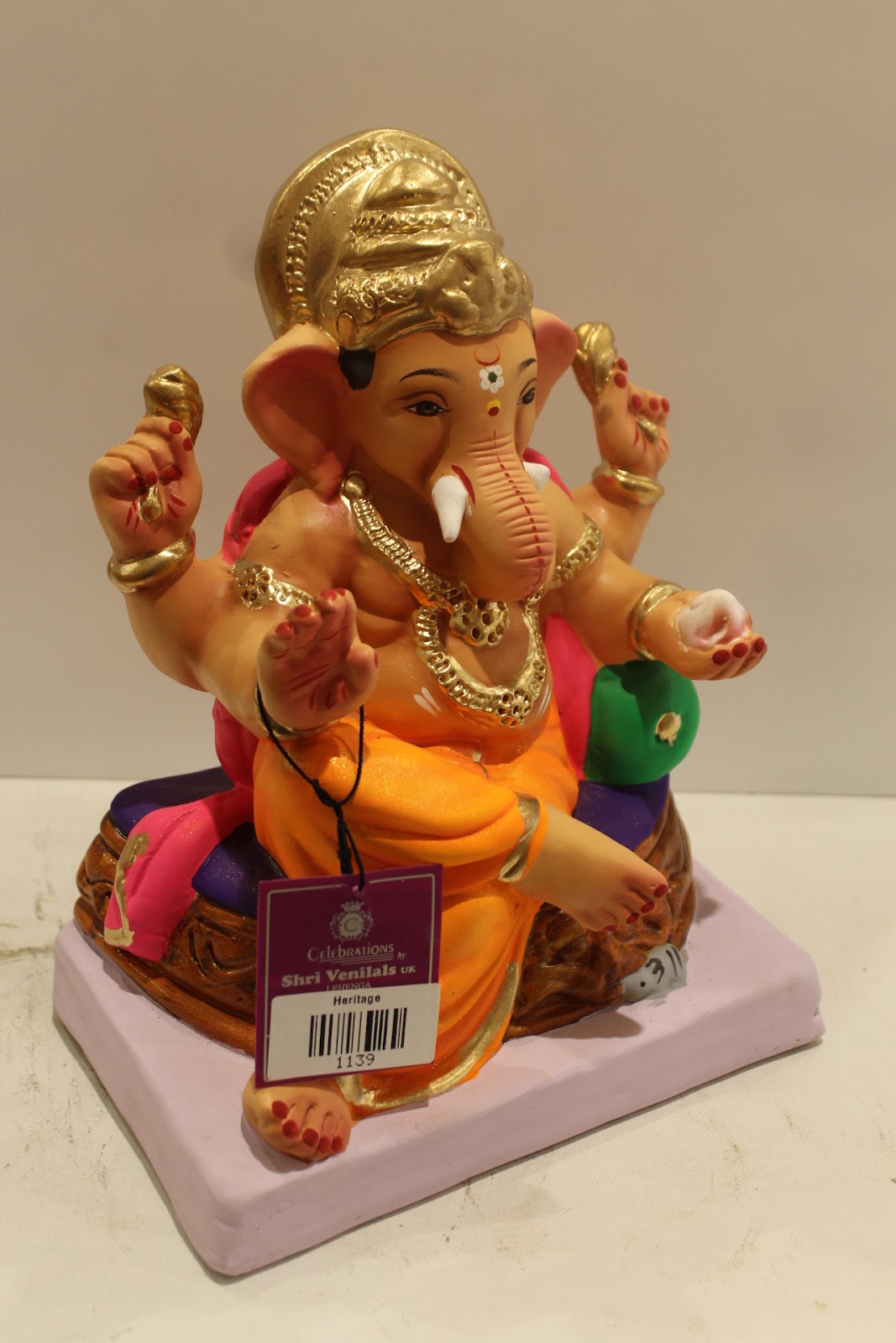 Eco-friendly clay Ganesh idol with pink khes, orange dhoti and basket throne, side view