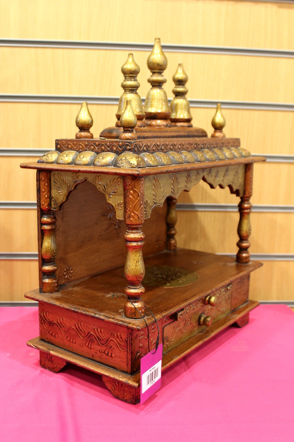 Open wooden mandir shown at an angle showing carved side panels