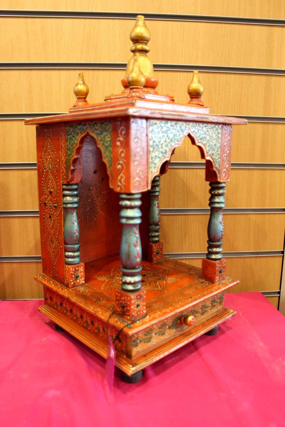 Orange and green painted mandir shown at a side angle