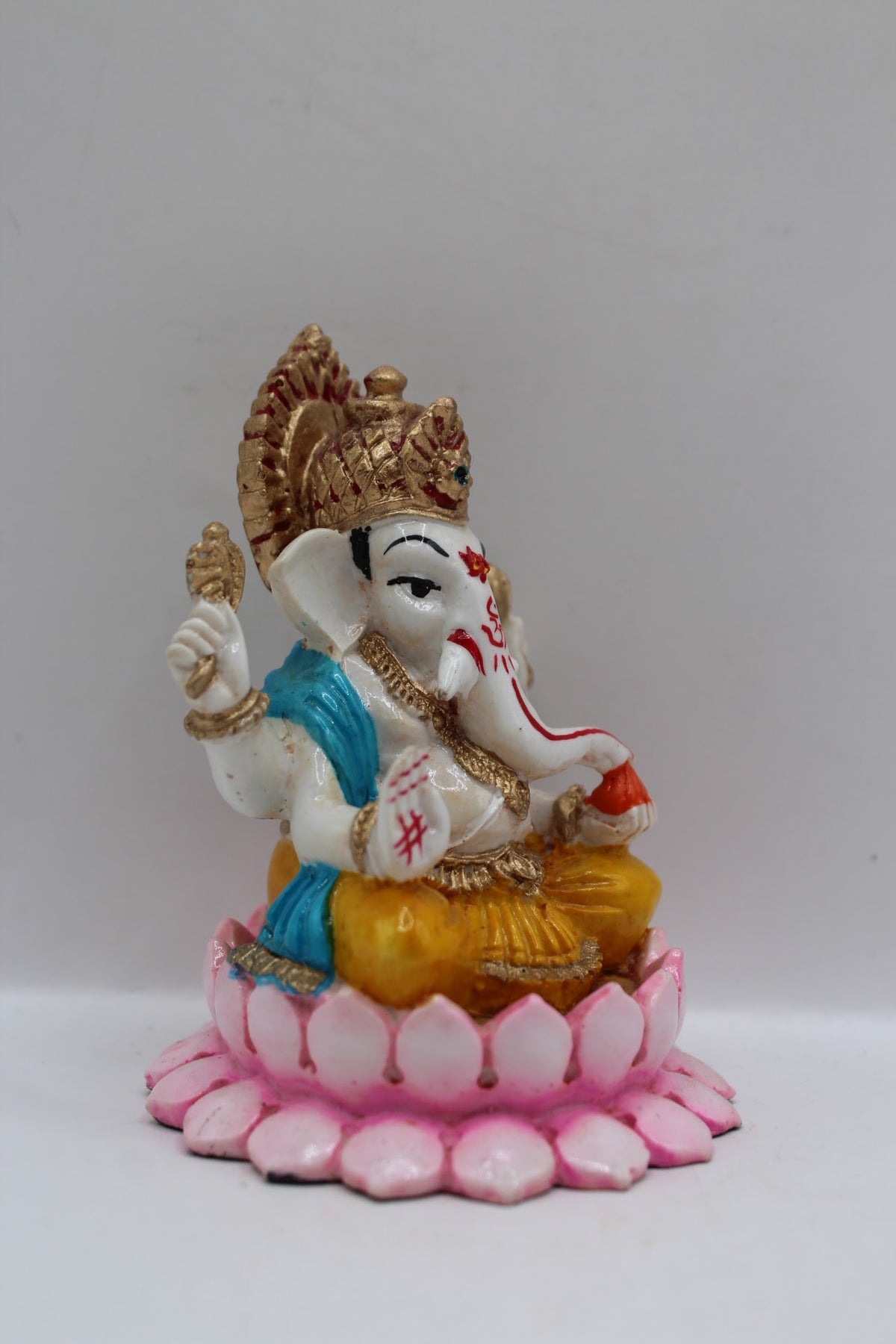 Resin Ganesh murti on pink lotus, yellow dhoti, left side view