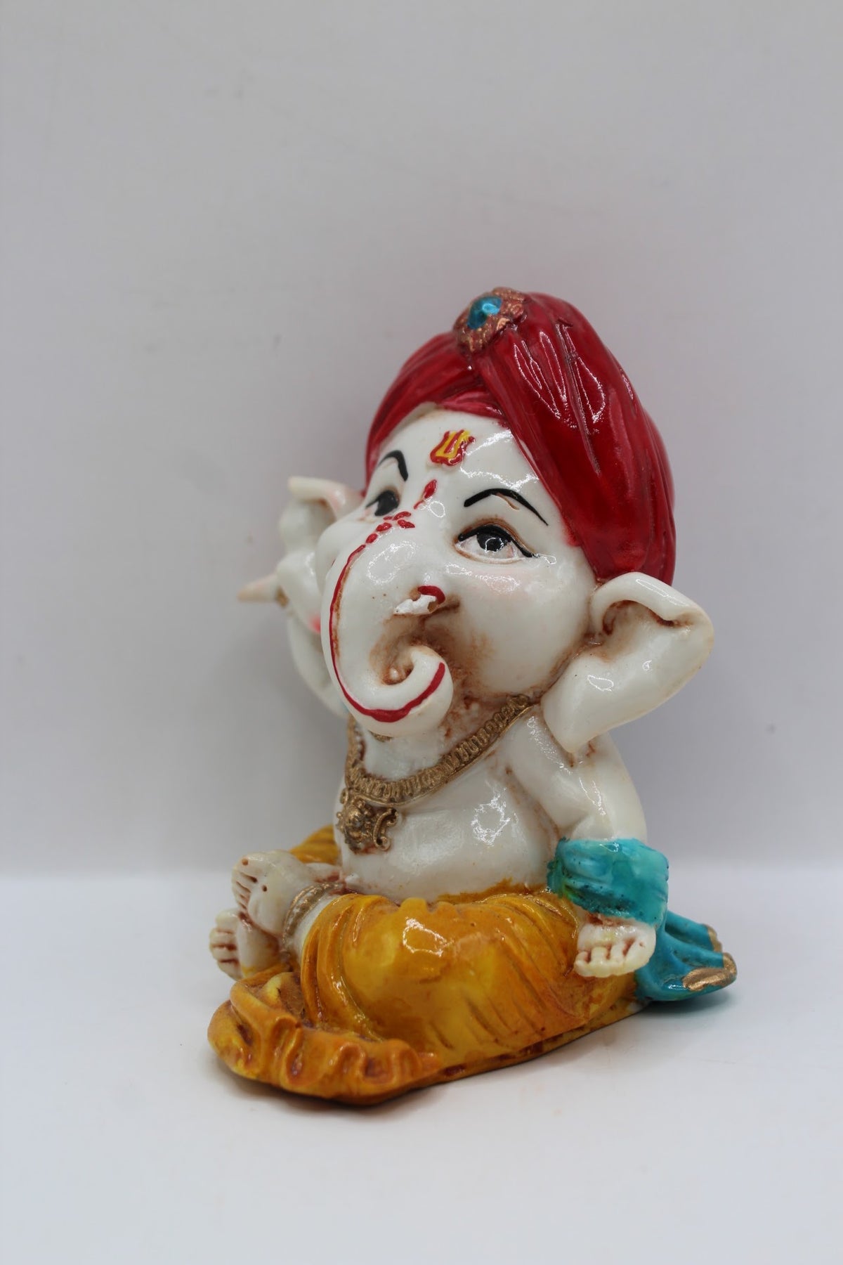 Baby Ganesh murti, red turban and blue scarf, right side view