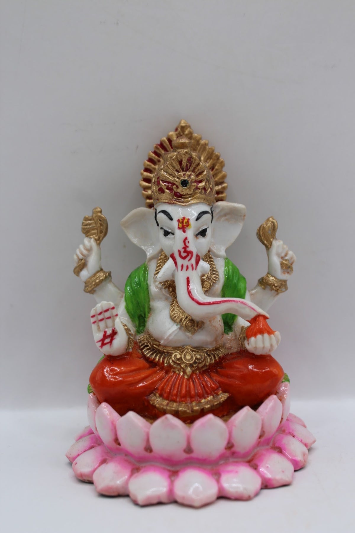 Resin Ganesh murti on pink lotus, orange dhoti, front view