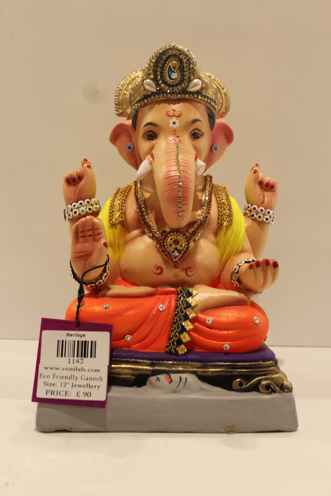 Eco-friendly clay Ganesh idol in jewellery style with yellow khes and orange dhoti, front view