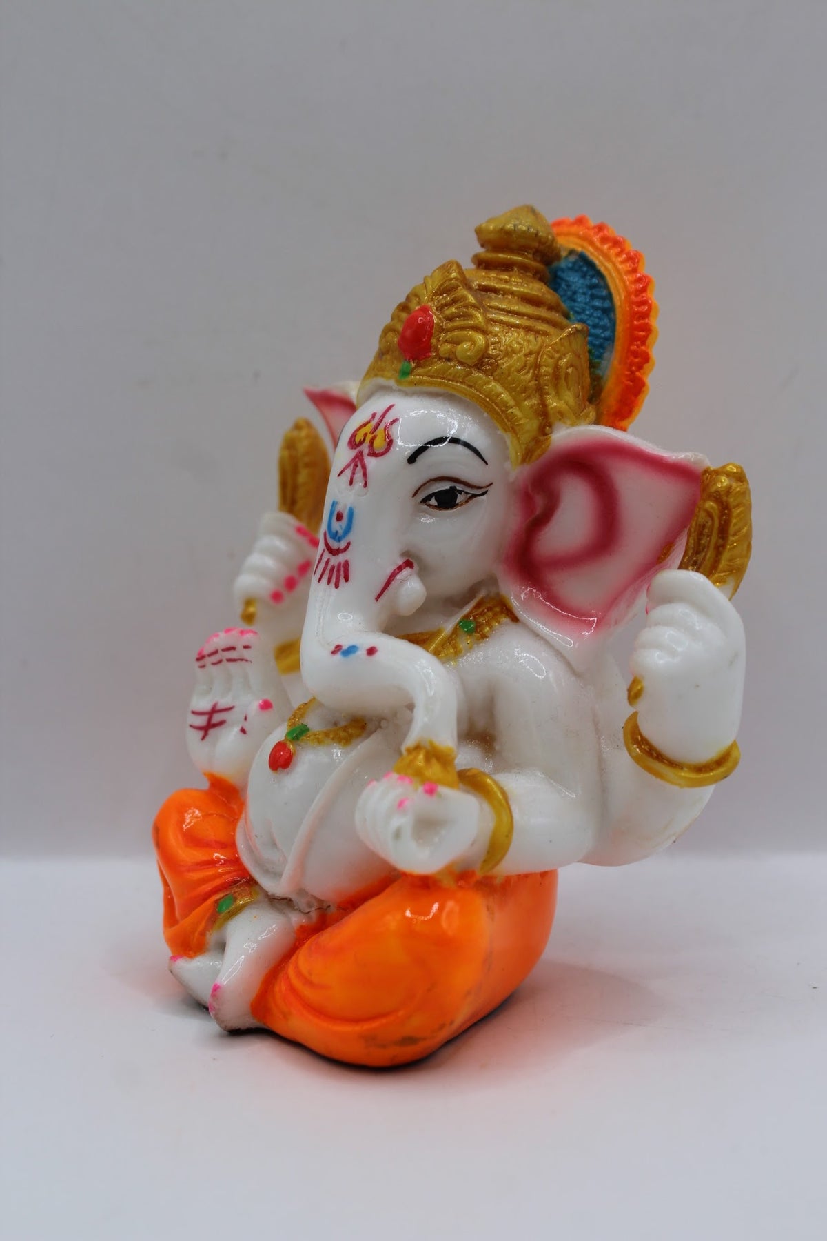 Small white resin Ganesh murti, orange dhoti, right side view