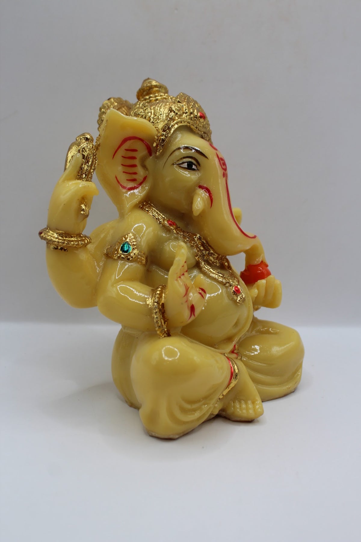 Cream resin Ganesh murti seated, gold crown, left side view