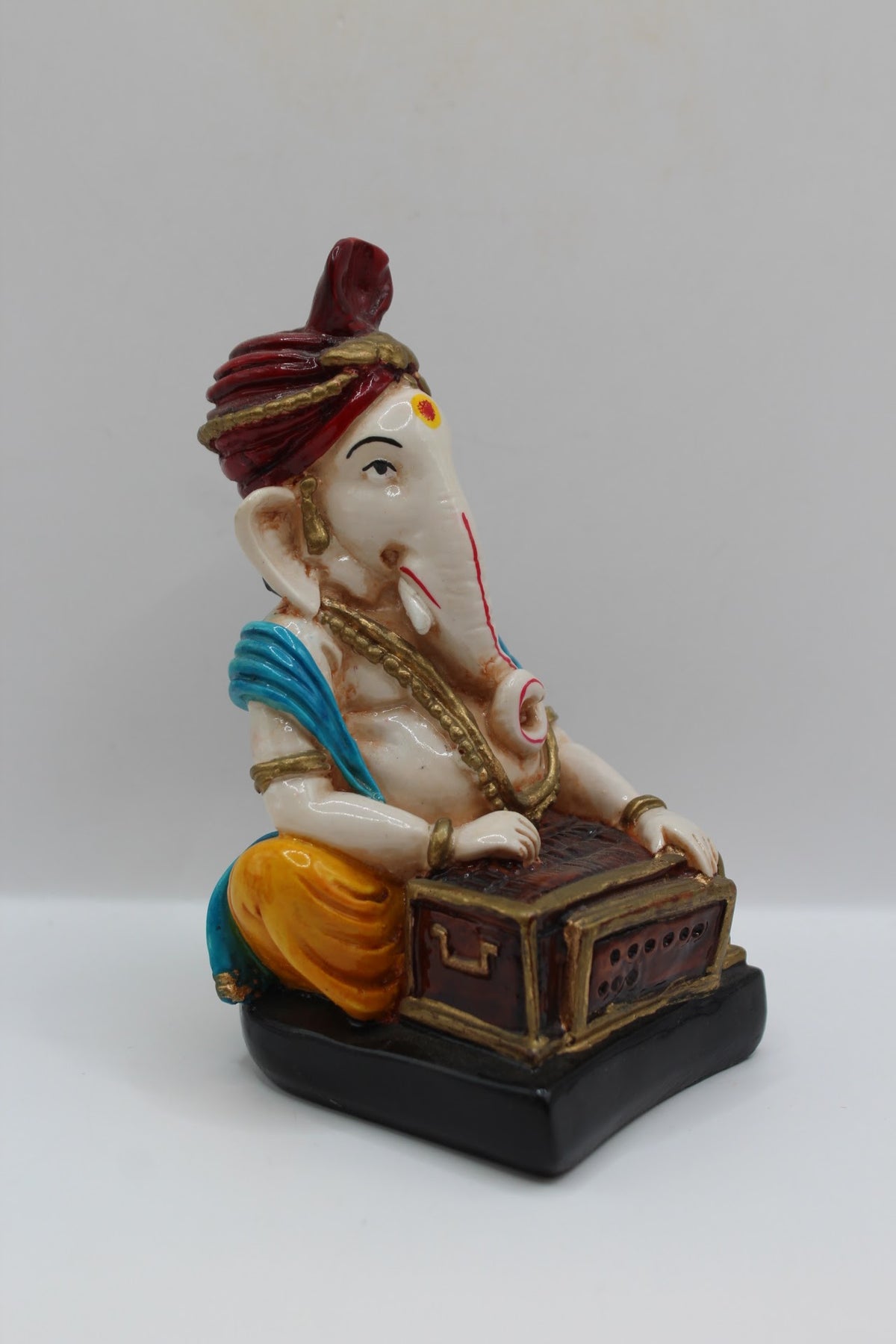 Resin Ganesh murti playing harmonium, red turban, left side view