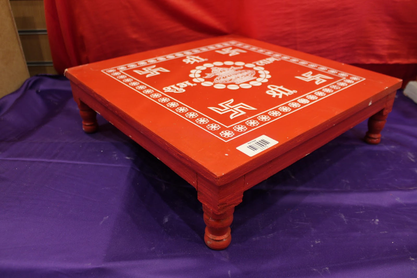 Red wooden bajot pooja chowki angled view showing turned legs