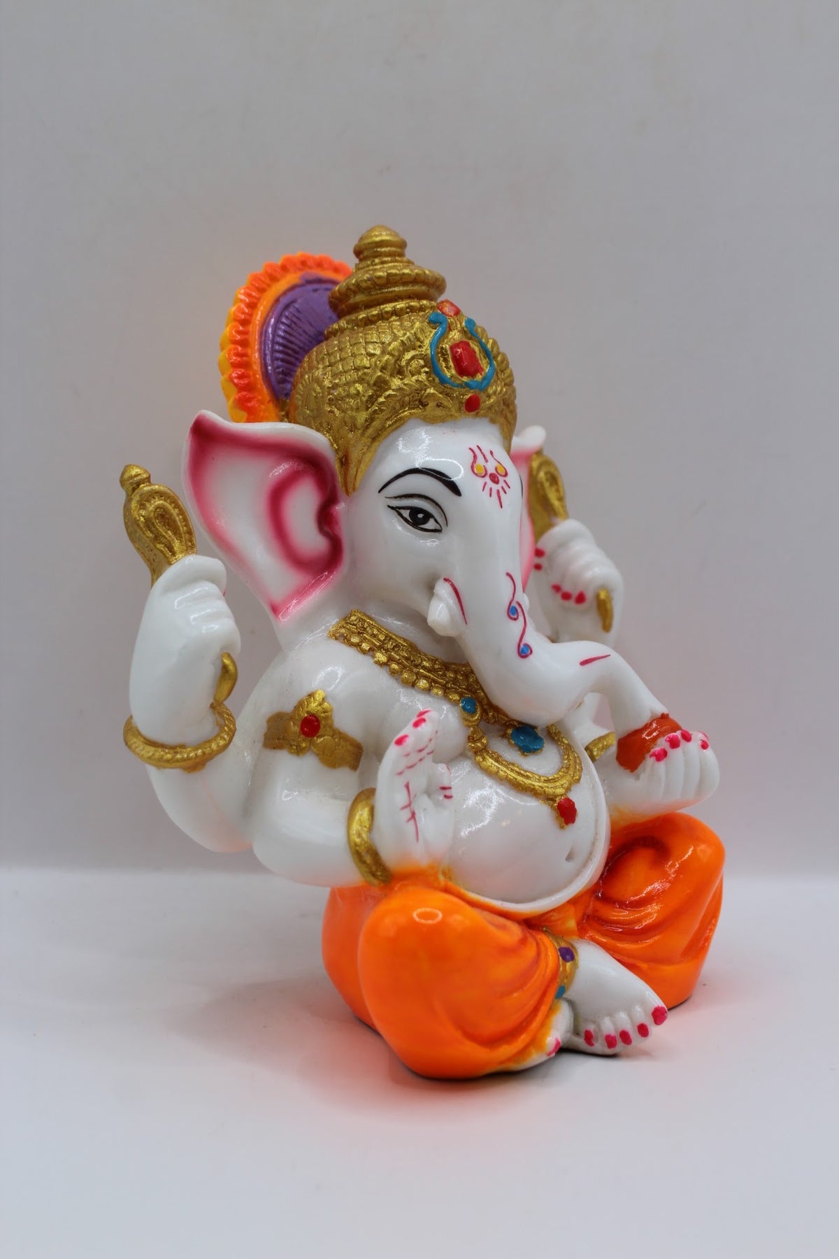 White resin Ganesh murti, orange dhoti, left side view