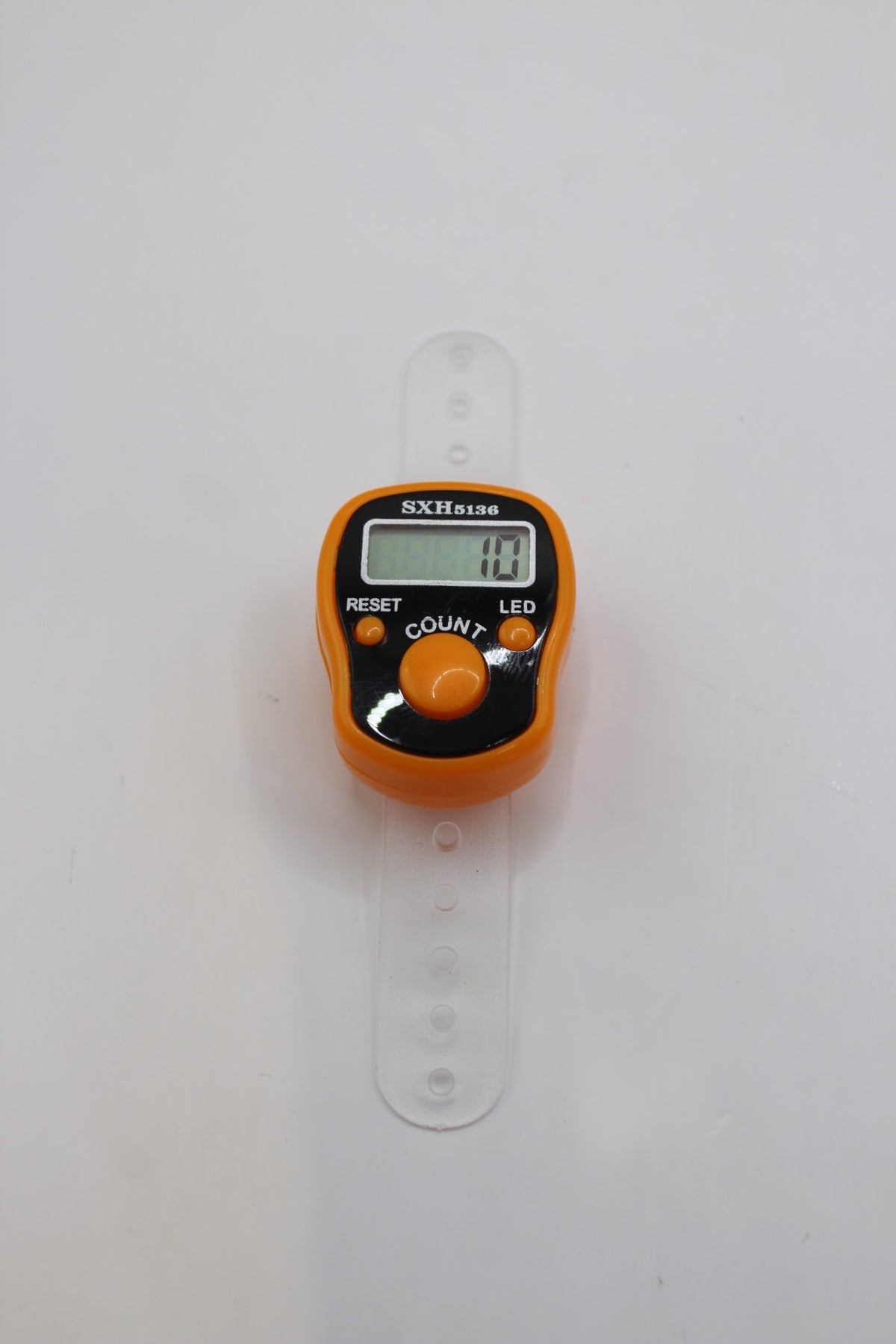 Digital finger counter on its finger strap, orange colour