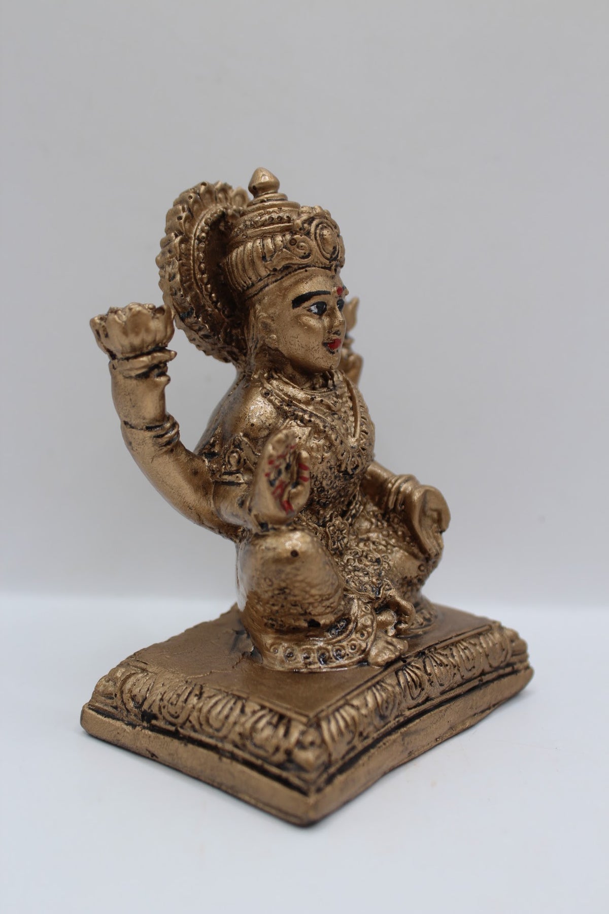 Antique gold resin Laxmi murti seated on square base, left side view
