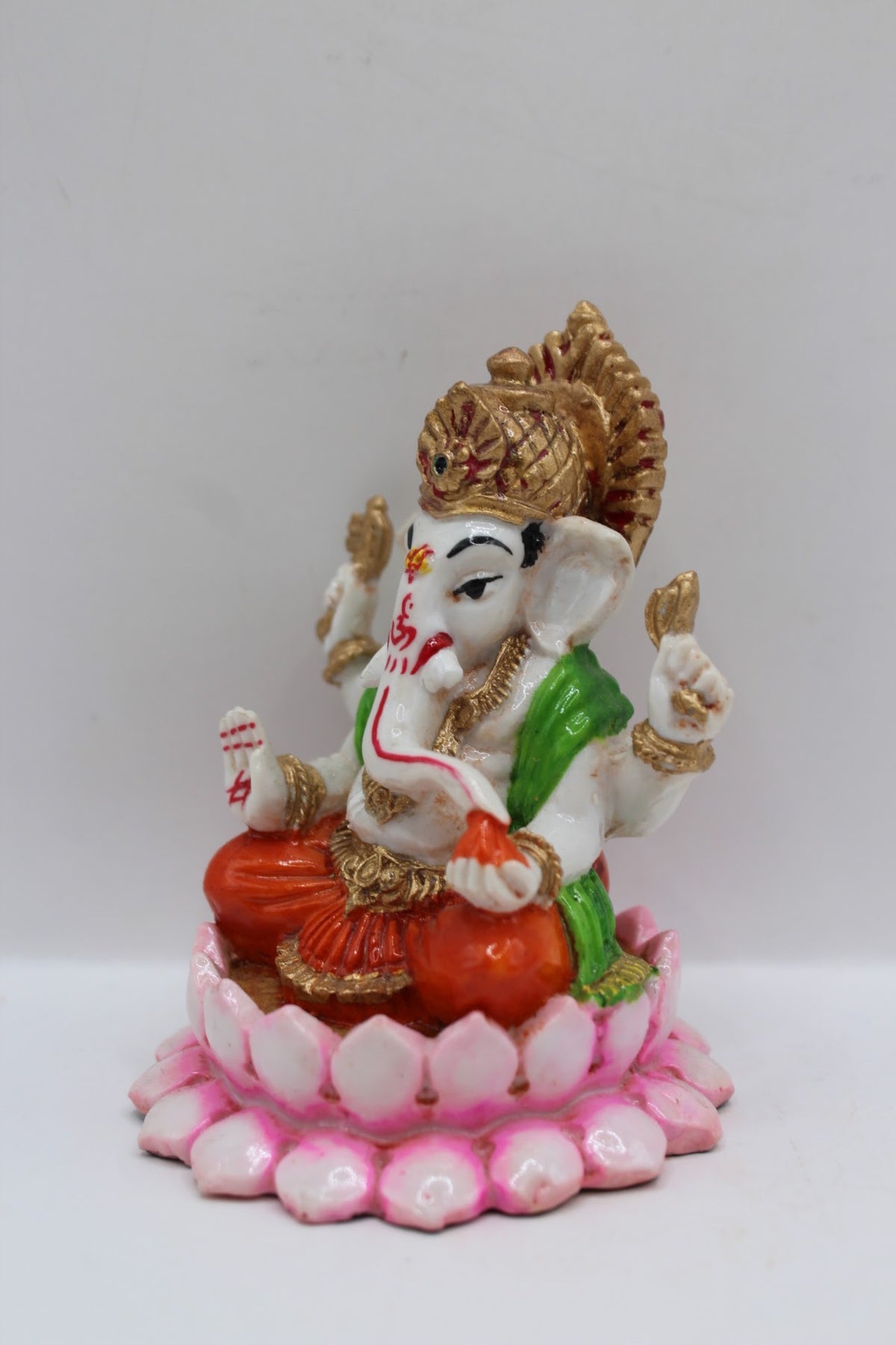 Resin Ganesh murti on pink lotus, orange dhoti, right side view