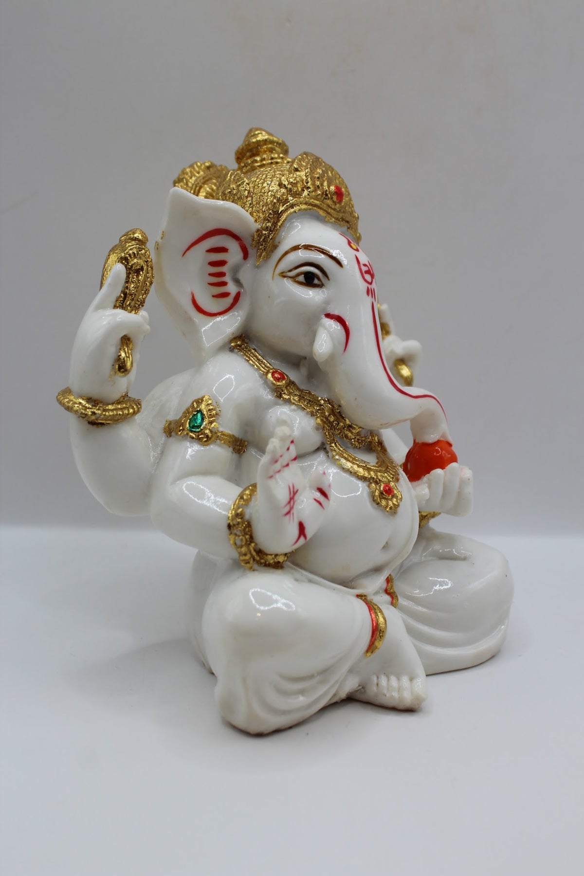 White and gold resin Ganesh murti seated, left side view