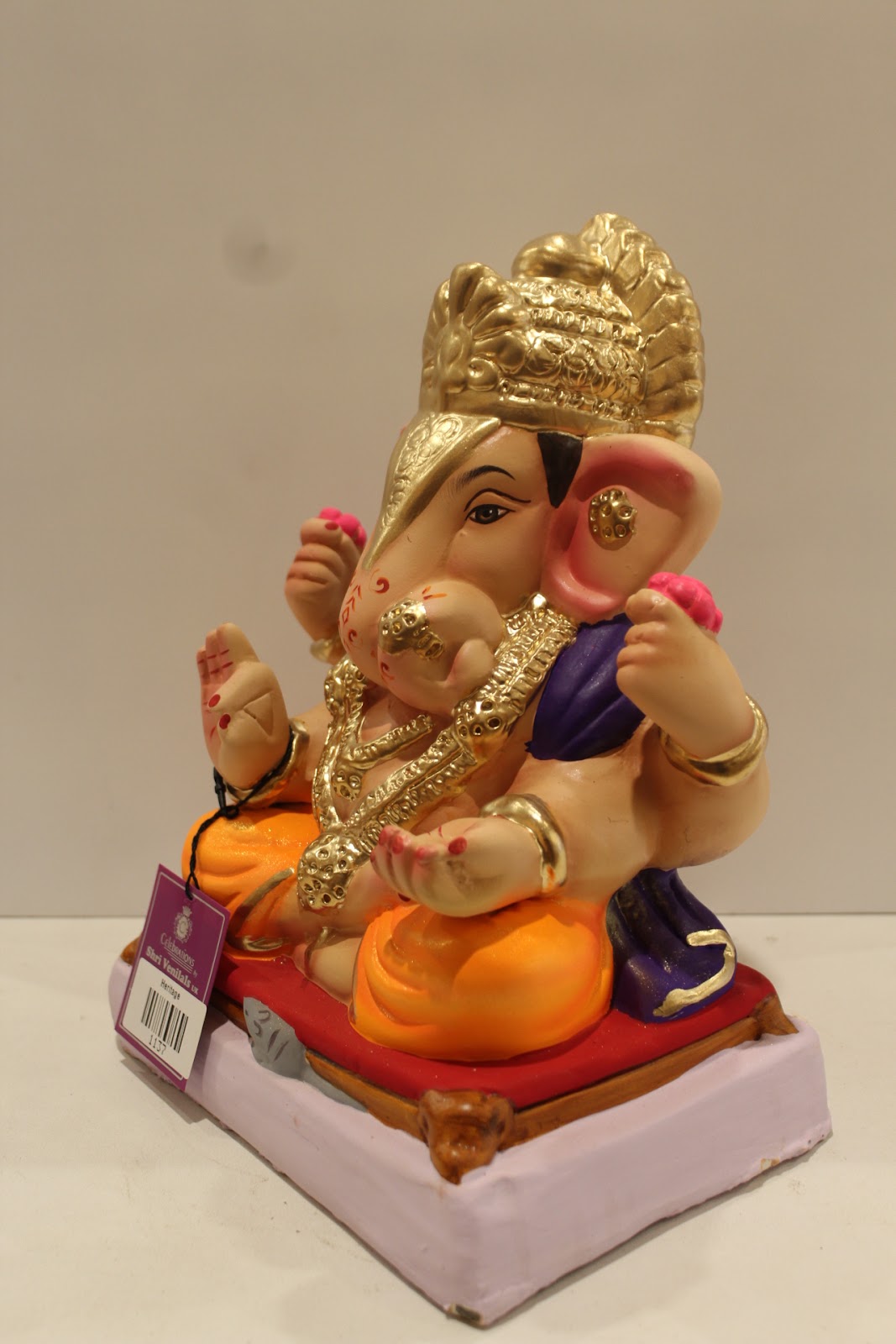 Eco-friendly clay Ganesh idol with purple shawl and orange dhoti, side view