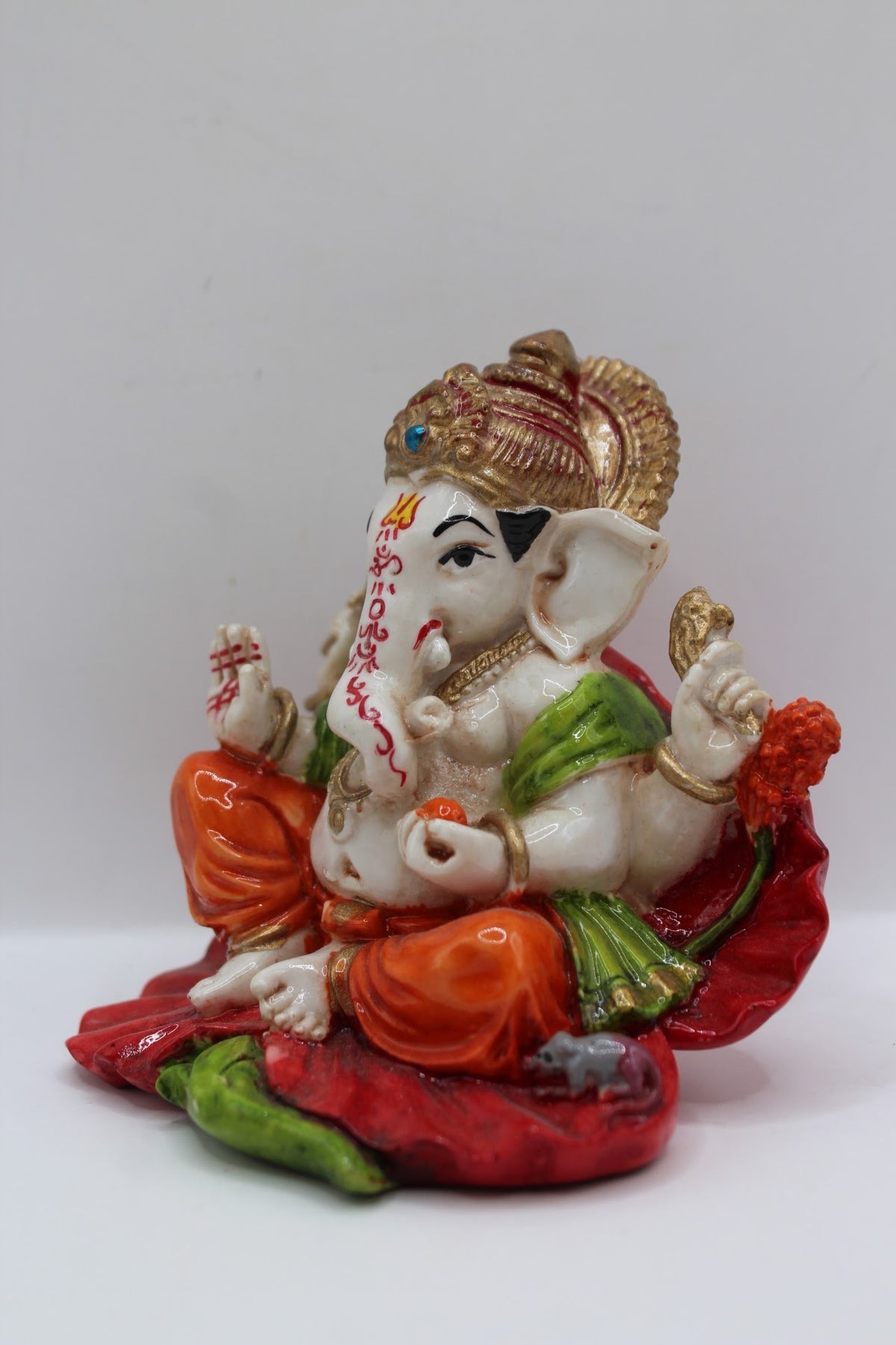 Resin Ganesh murti on red leaf, orange dhoti, right side view