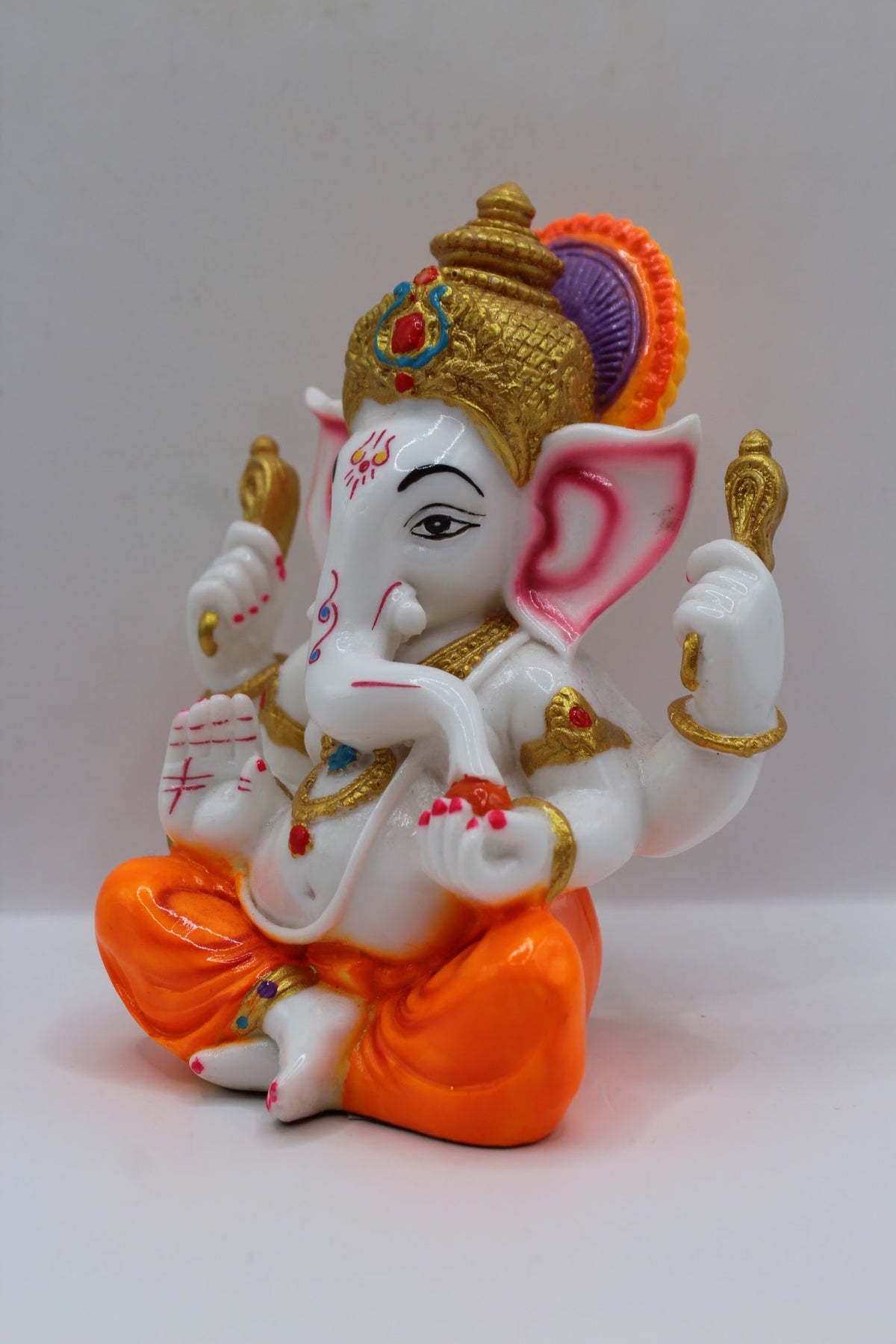 White resin Ganesh murti, orange dhoti, right side view