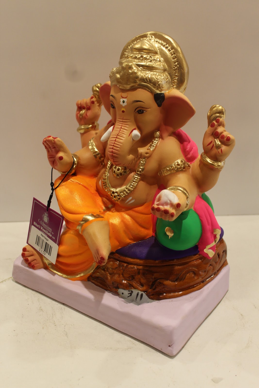 Eco-friendly clay Ganesh idol with pink khes, orange dhoti and basket throne, side view
