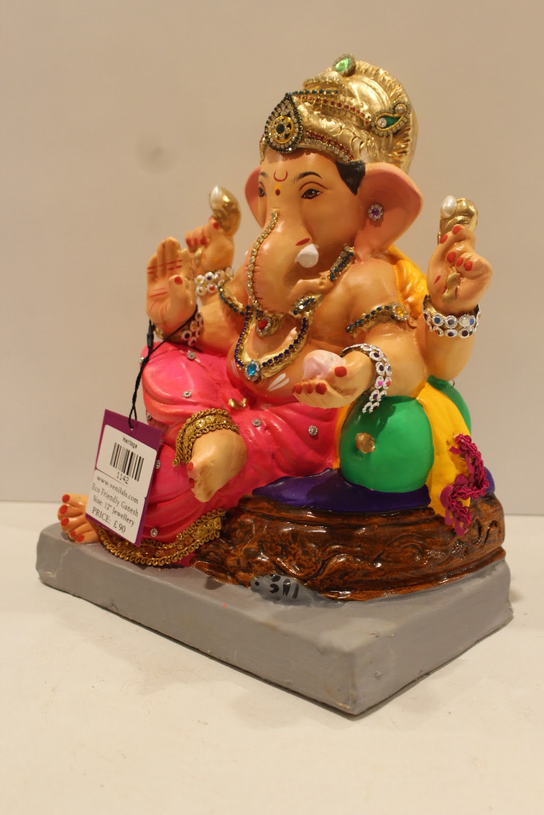 Eco-friendly clay Ganesh idol in jewellery style with rani pink dhoti and basket throne, side view