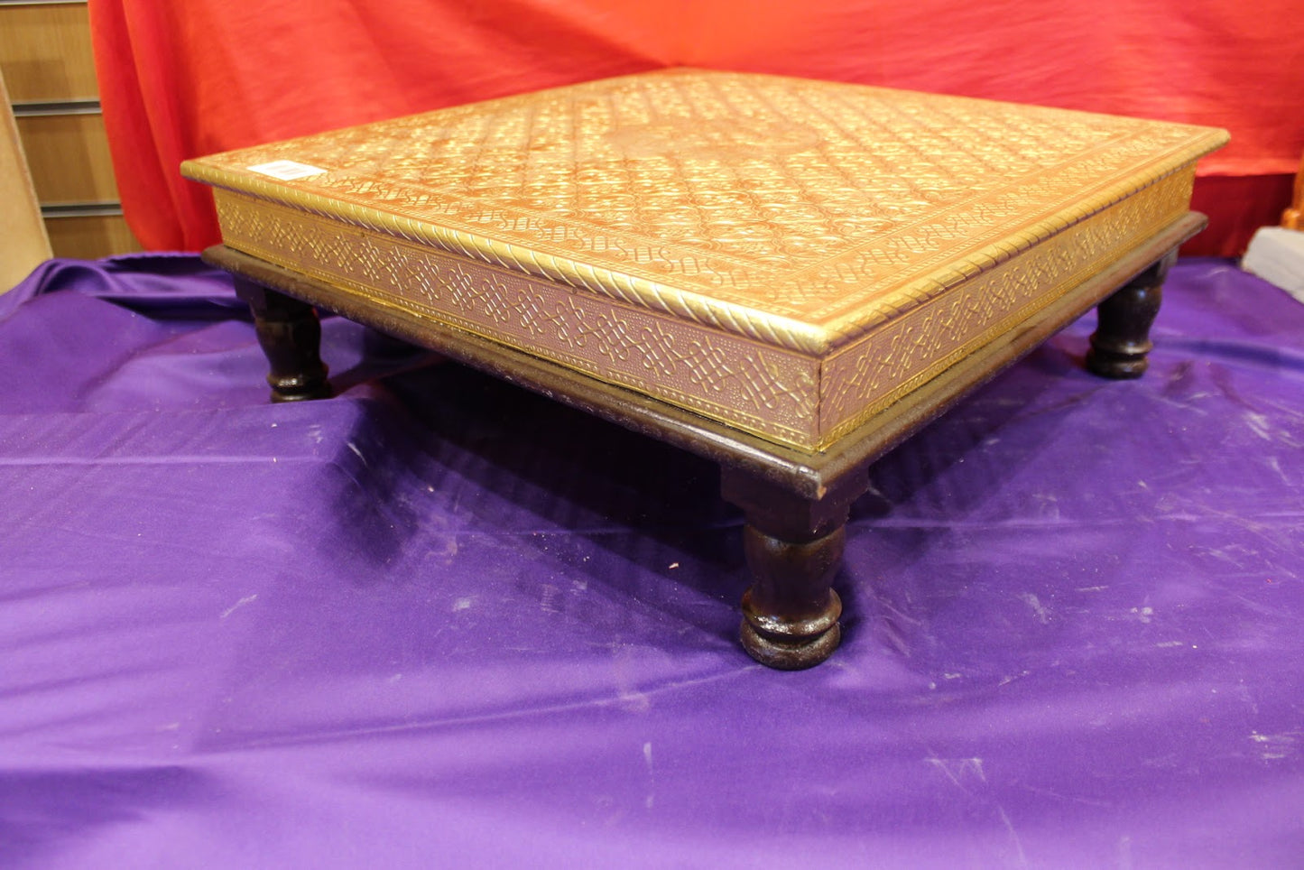 Gold embossed bajot pooja chowki angled view with dark turned legs