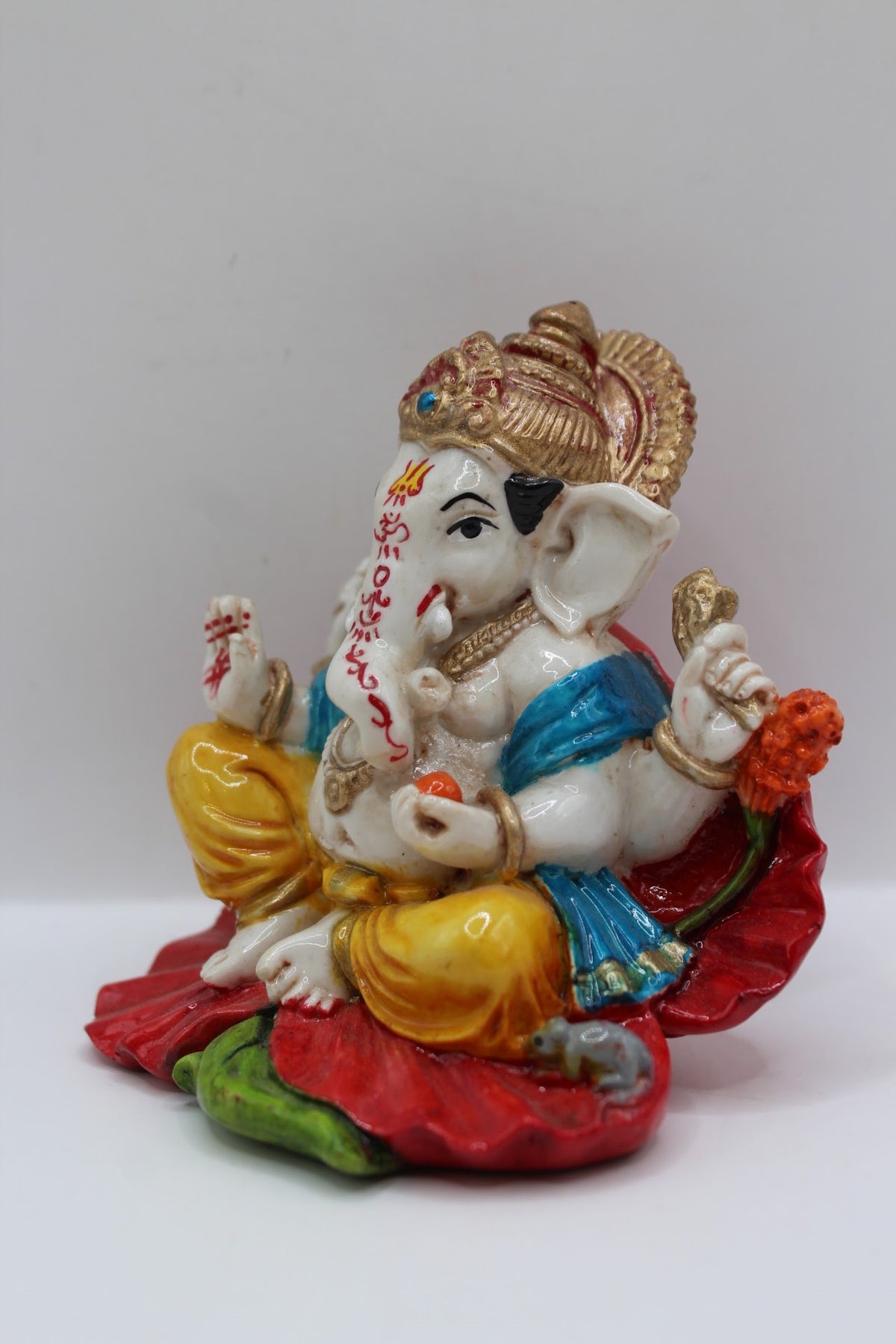 Resin Ganesh murti on red leaf, yellow dhoti, right side view