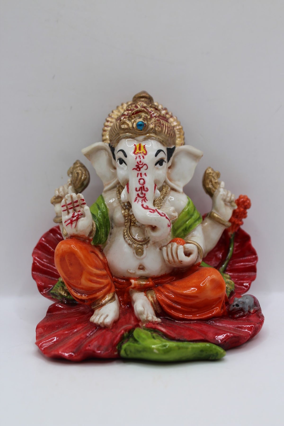 Resin Ganesh murti on red leaf, orange dhoti, front view