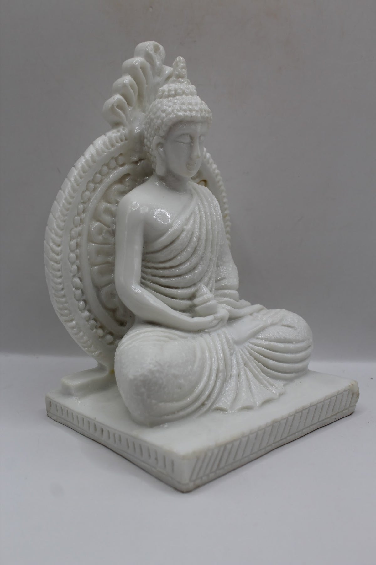White resin Buddha statue meditating with halo, left side view