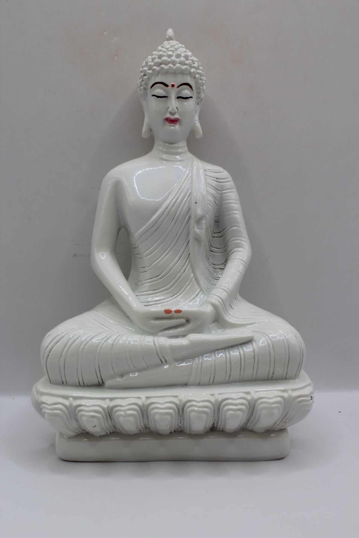 White resin Buddha statue meditating on a lotus base, front view