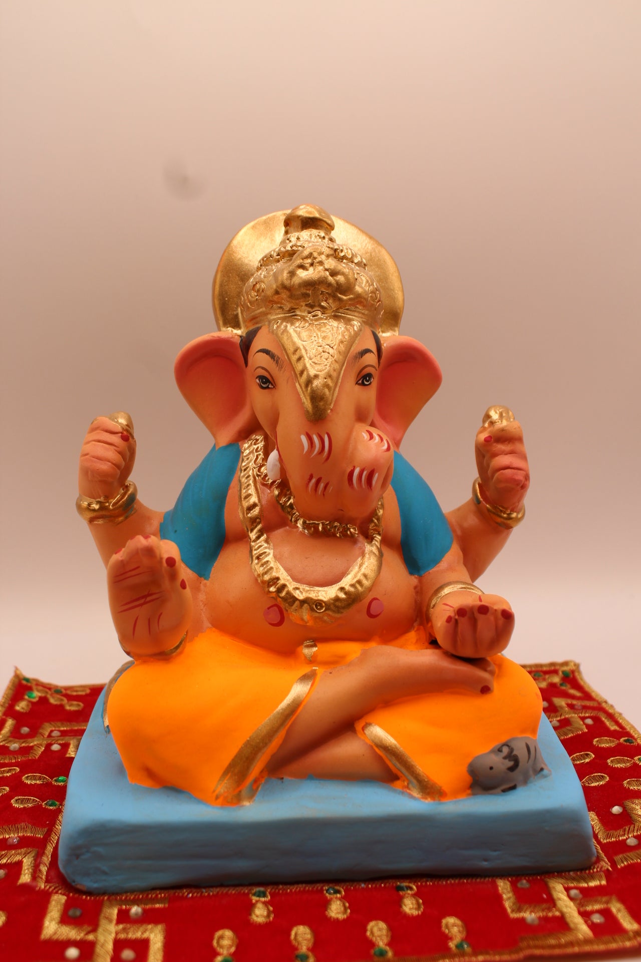 Eco-friendly 8 inch Ganesh Visarjan idol in sky blue shawl and orange dhoti with gold trunk – front view