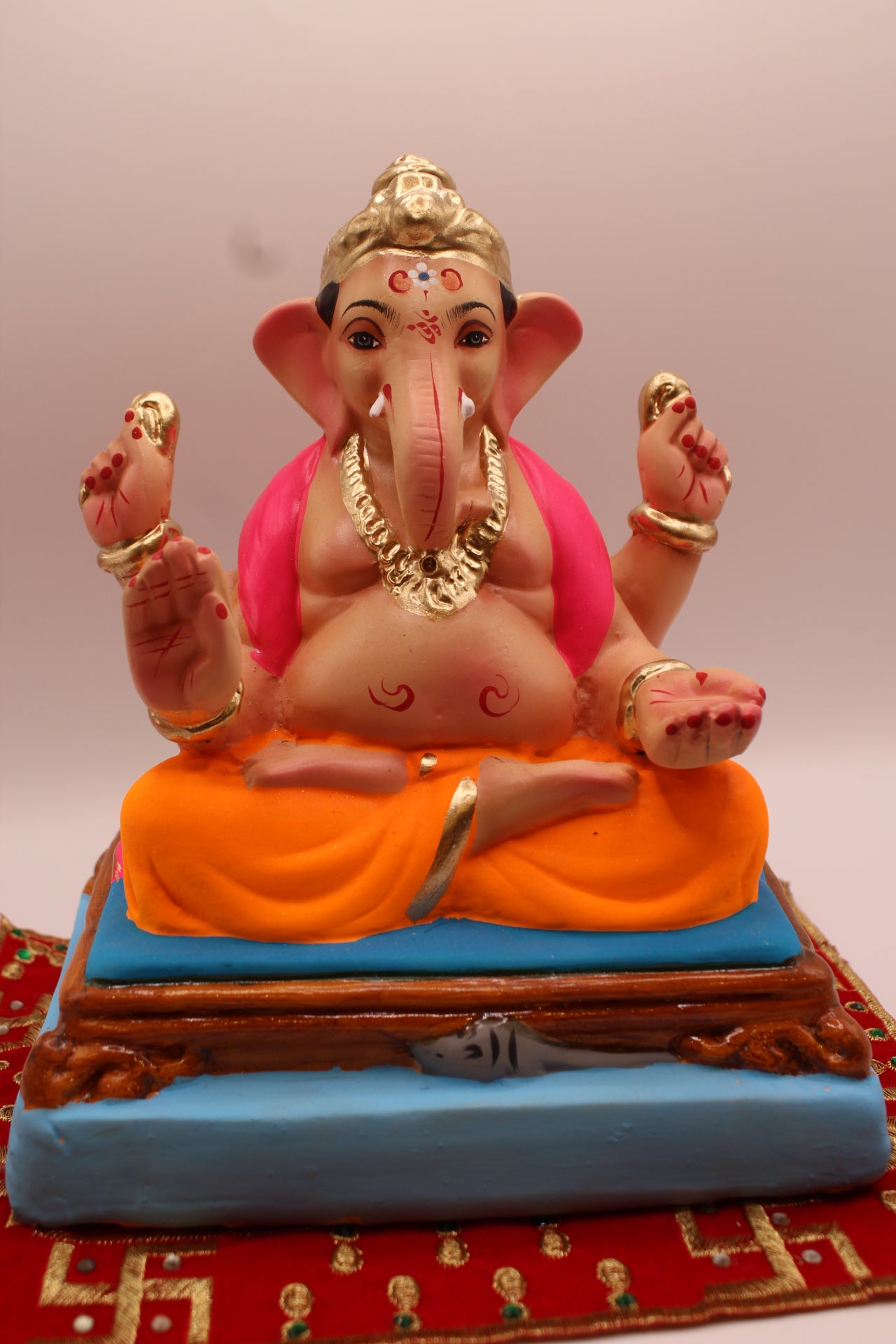 Eco-friendly 8 inch Ganesh Visarjan idol in pink shawl and orange dhoti with gold topknot – front view