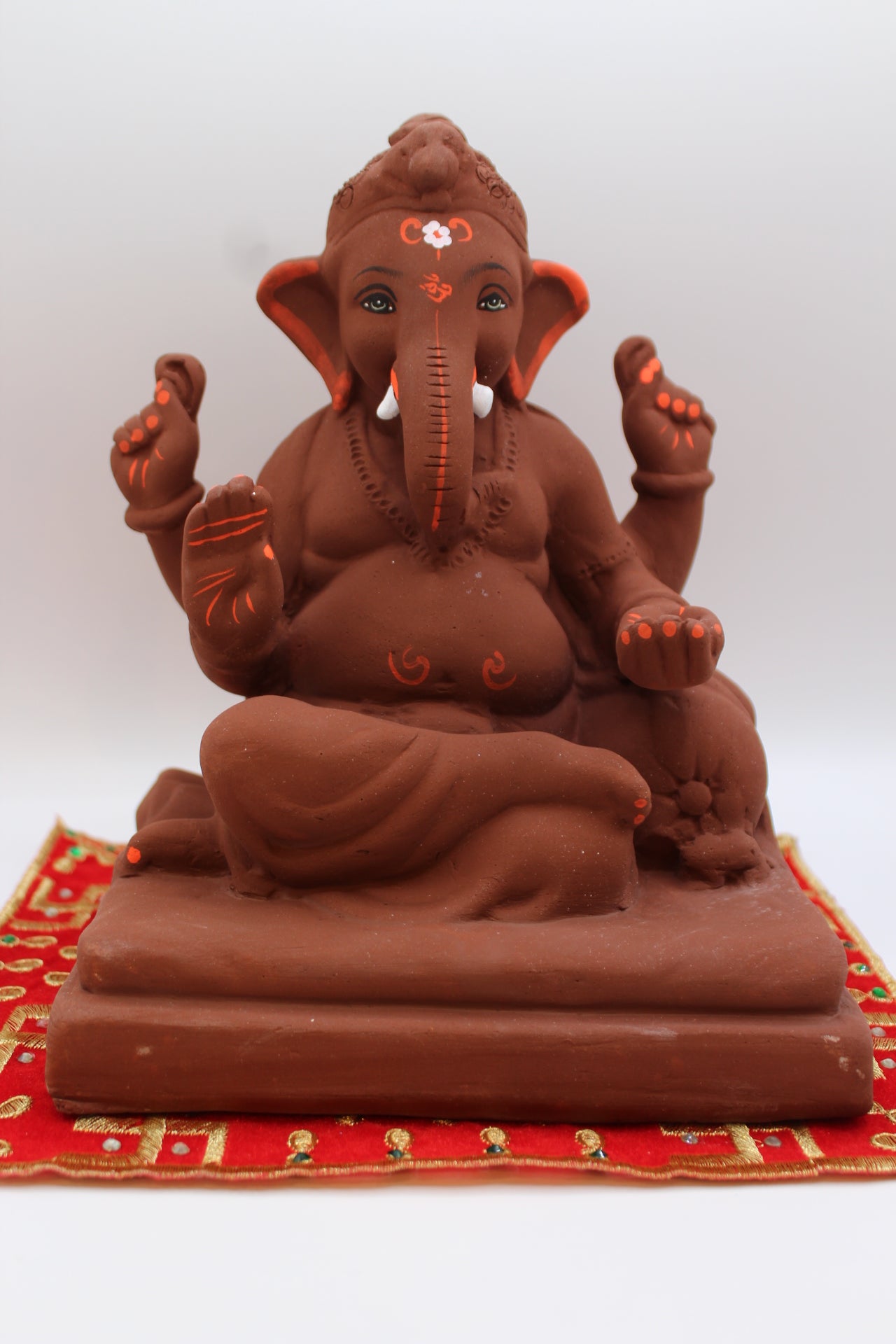 Natural terracotta eco-friendly 8 inch Ganesh Visarjan idol with topknot and orange accents – front view