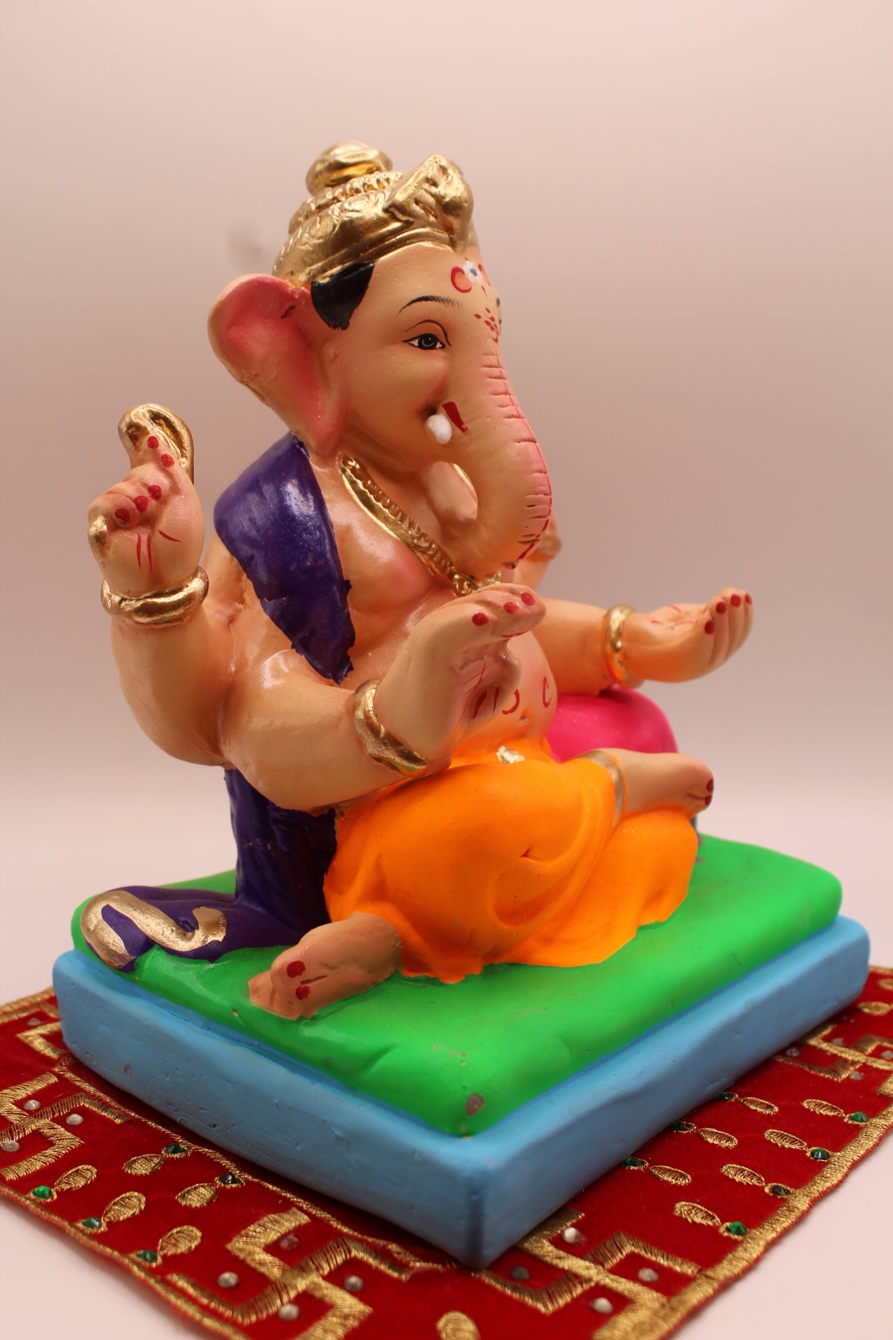 Eco-friendly 8 inch Ganesh Visarjan idol in purple shawl and orange dhoti – side view
