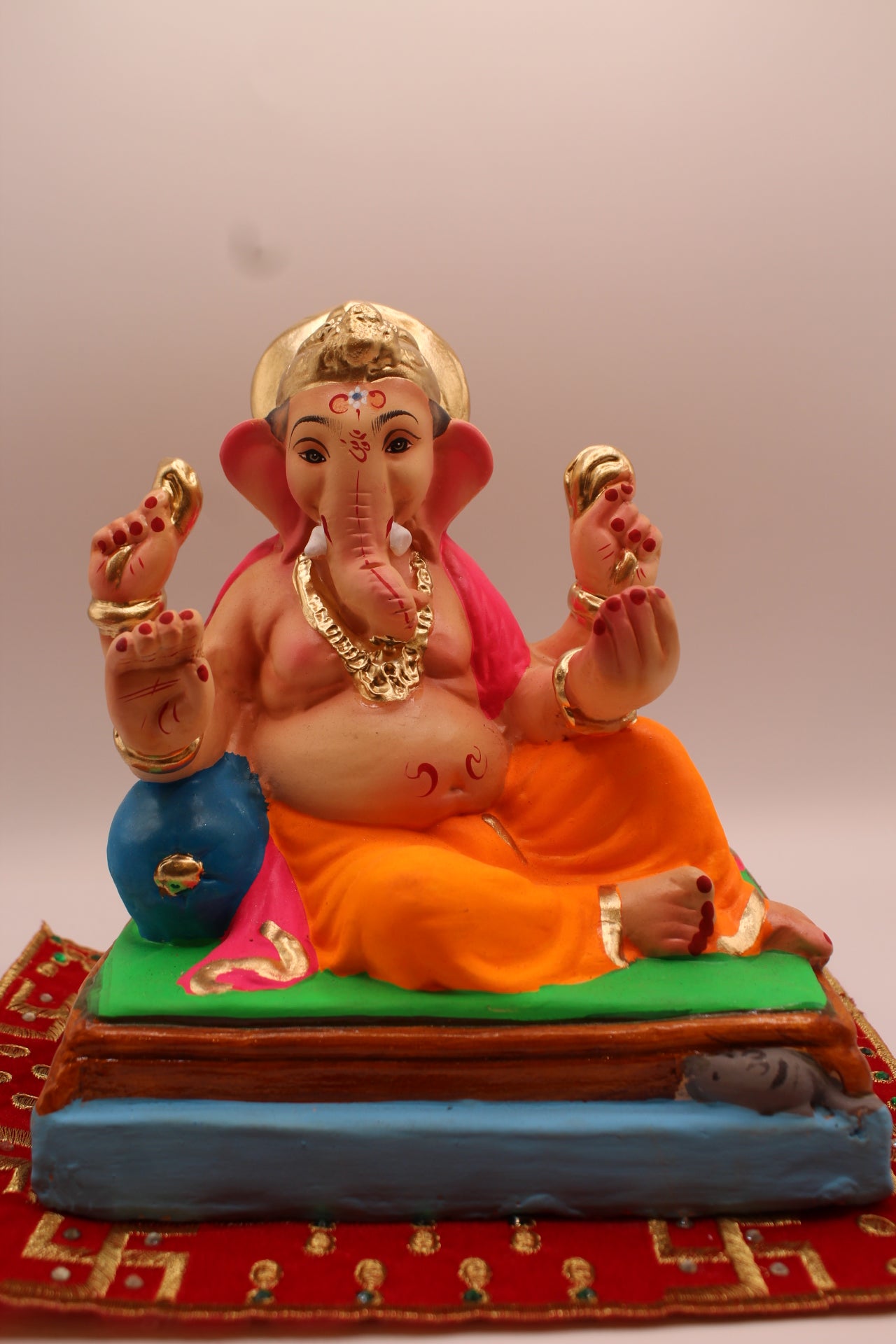Eco-friendly 8 inch Ganesh Visarjan idol in pink khes and orange dhoti, relaxed pose – front view