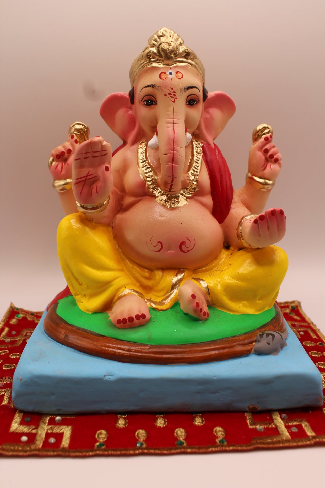 Eco-friendly 8 inch Ganesh Visarjan idol in red khes and yellow dhoti on round green mat – front view