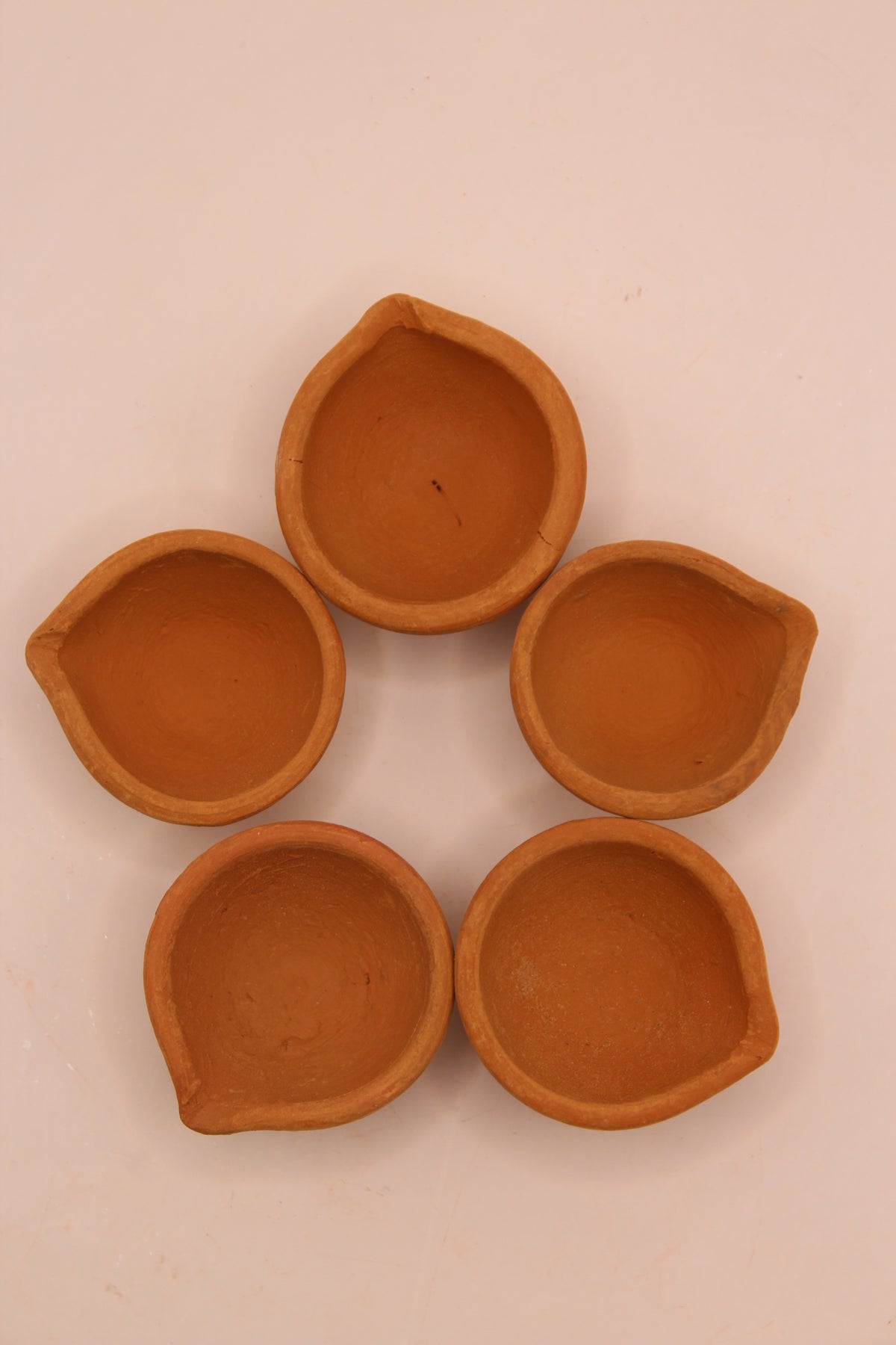 Five plain clay diyas, top view