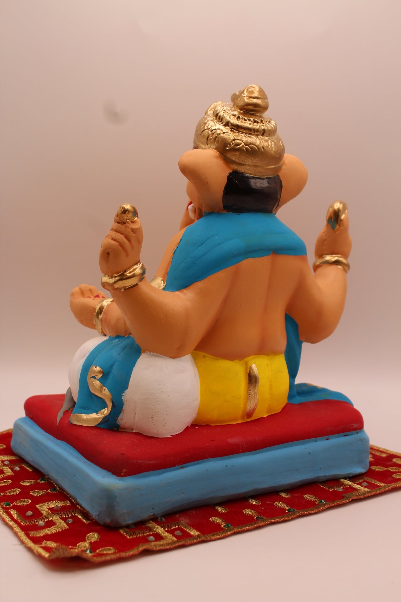Back view – teal khes and yellow dhoti on a red cushion