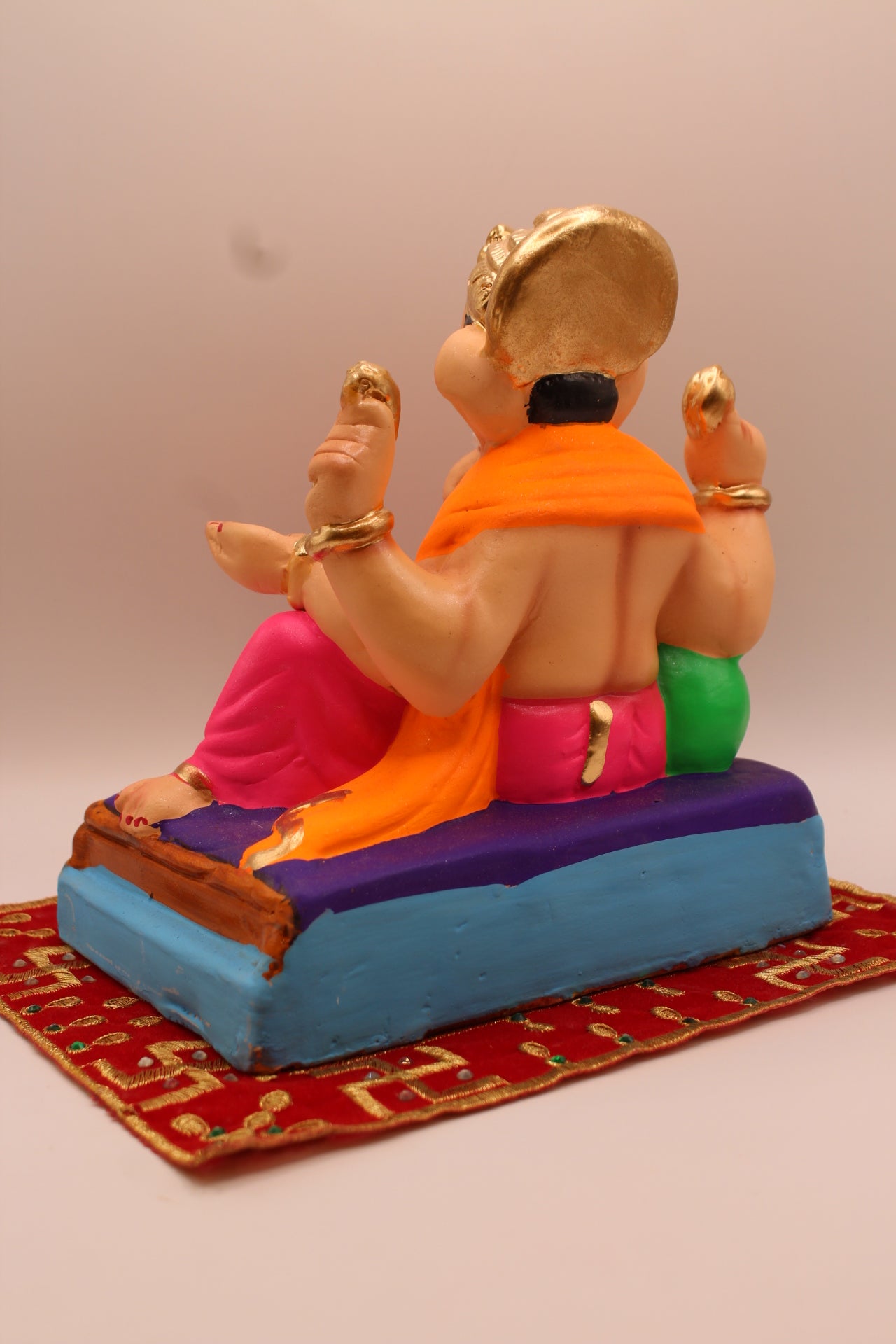Back view – orange khes and pink dhoti reclining against a green cushion