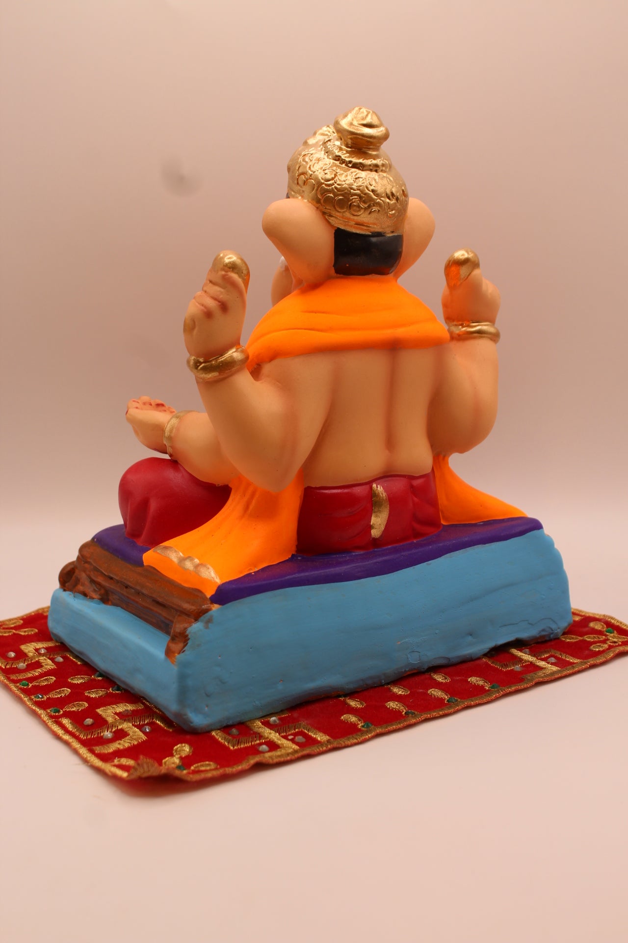 Back view – orange khes and maroon dhoti on a purple mat