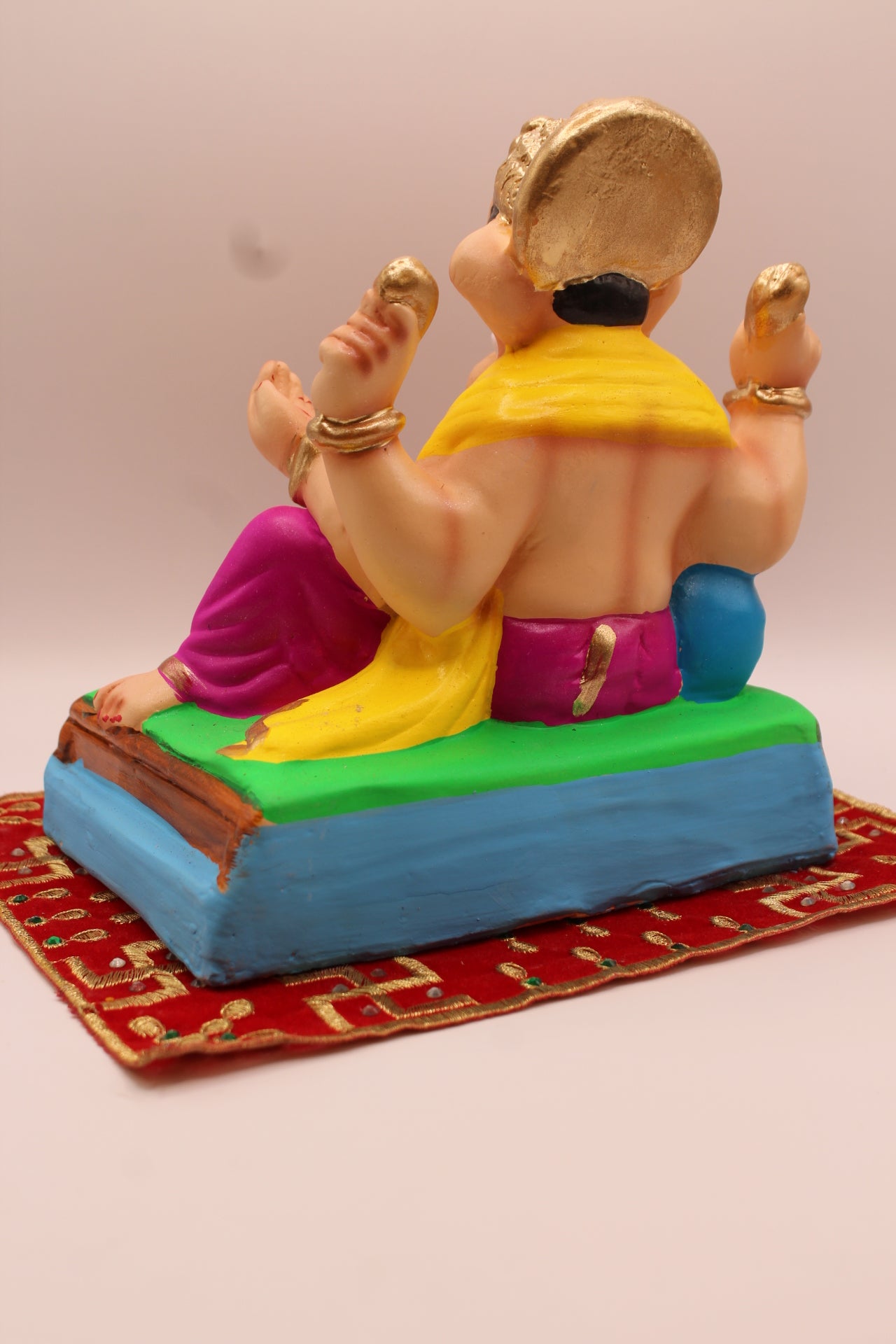 Back view – yellow khes and magenta dhoti leaning on a blue cushion