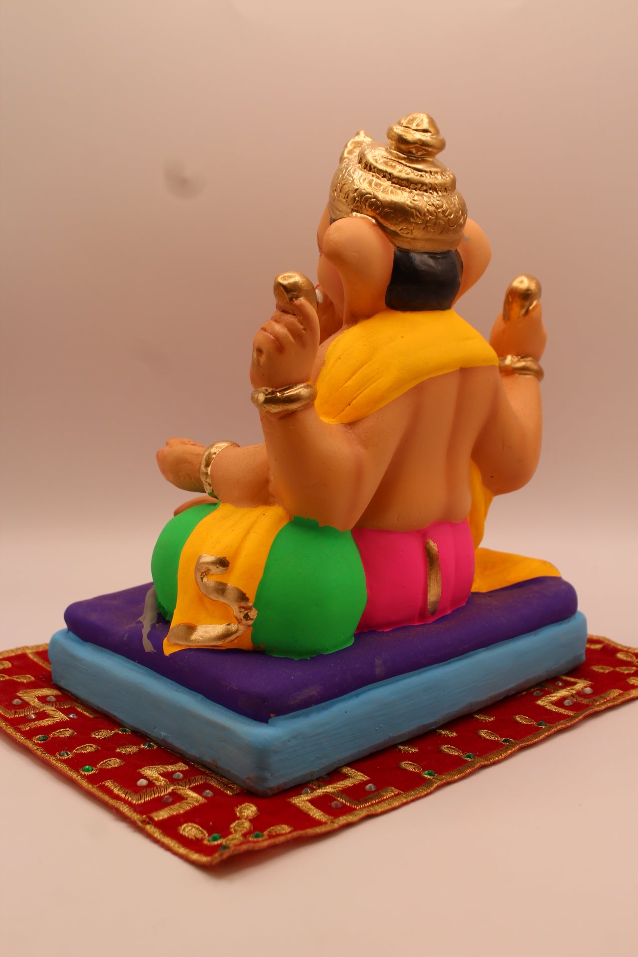 Back view – yellow khes and pink dhoti reclining on a purple mat