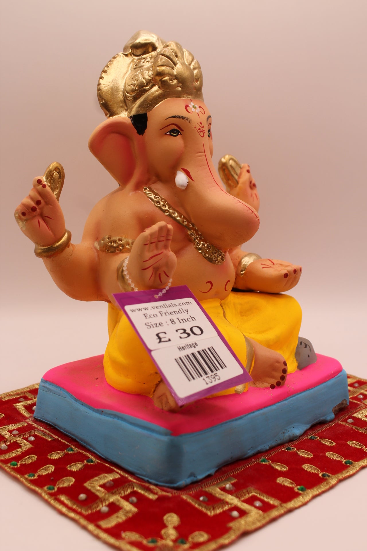 Side view – yellow dhoti and carved gold mukut on a pink mat