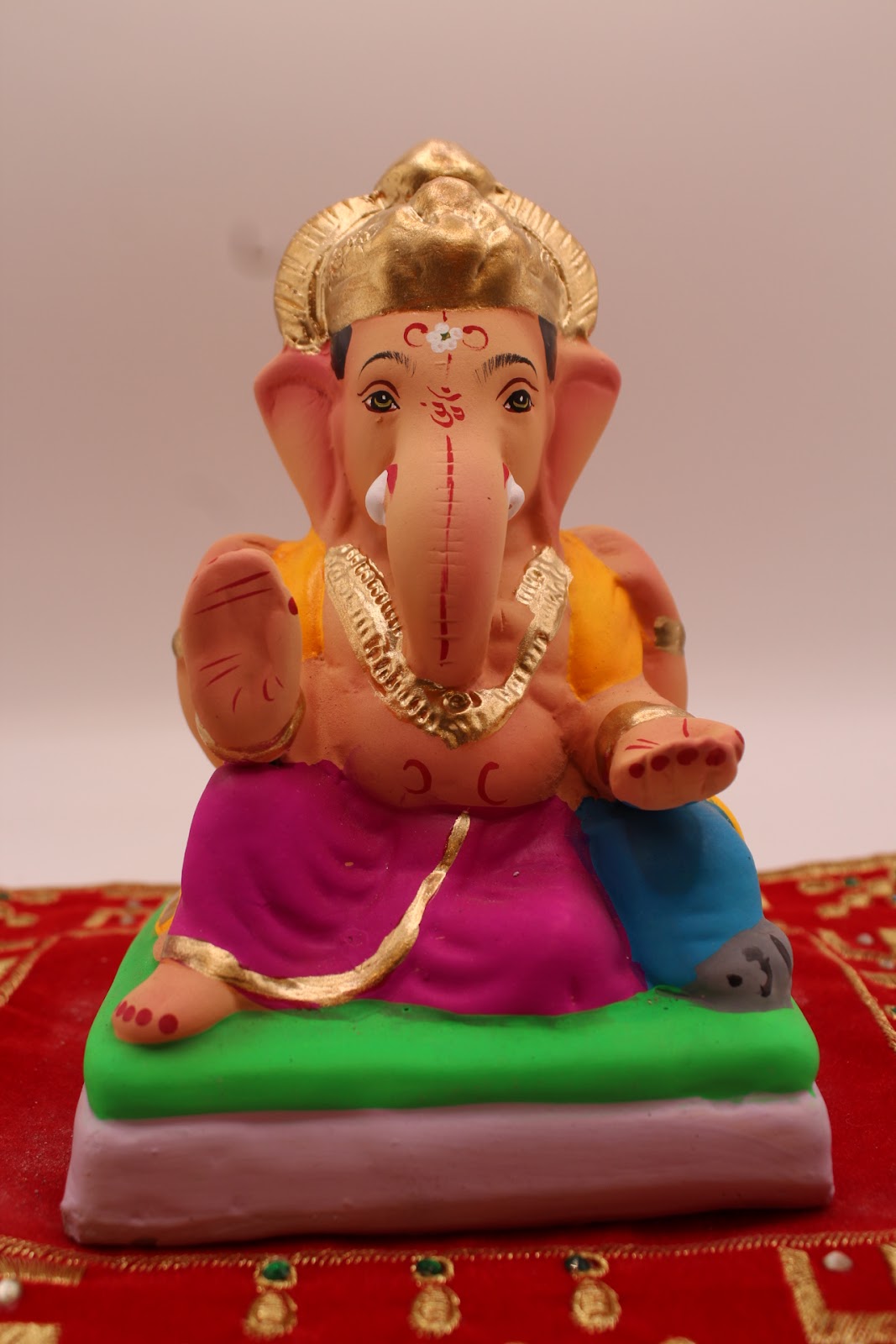Eco-friendly 6 inch Ganesh idol, marigold khes and magenta dhoti, front view