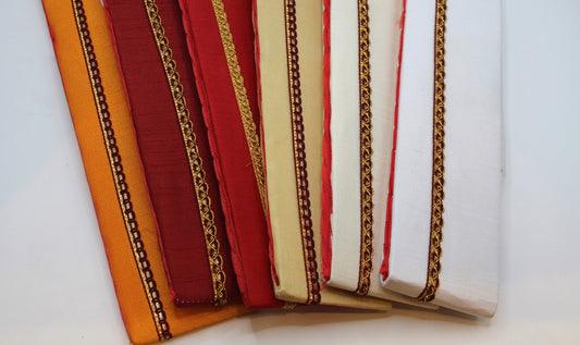 Gandhi topi colour range — saffron, maroon, red, champagne gold, off-white and white, each with a woven gold border