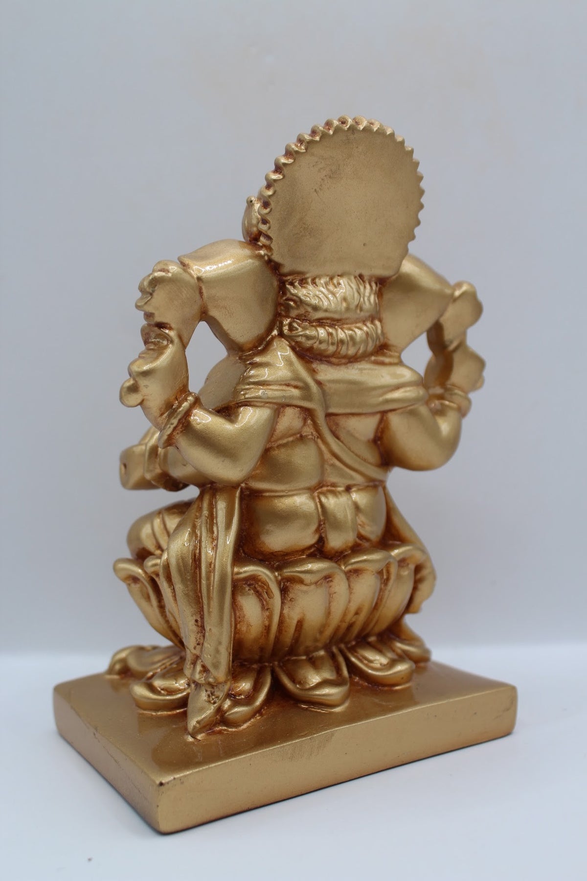 Gold resin Ganesh murti seated on a lotus, back view