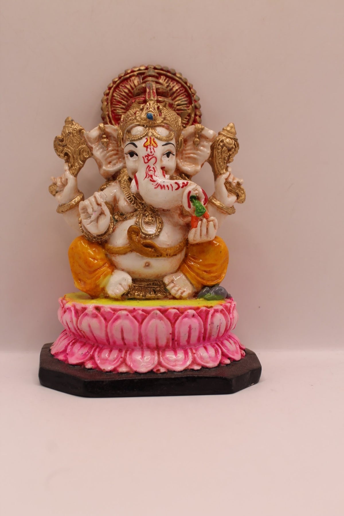 Resin Ganesh murti on pink lotus with yellow dhoti, front view